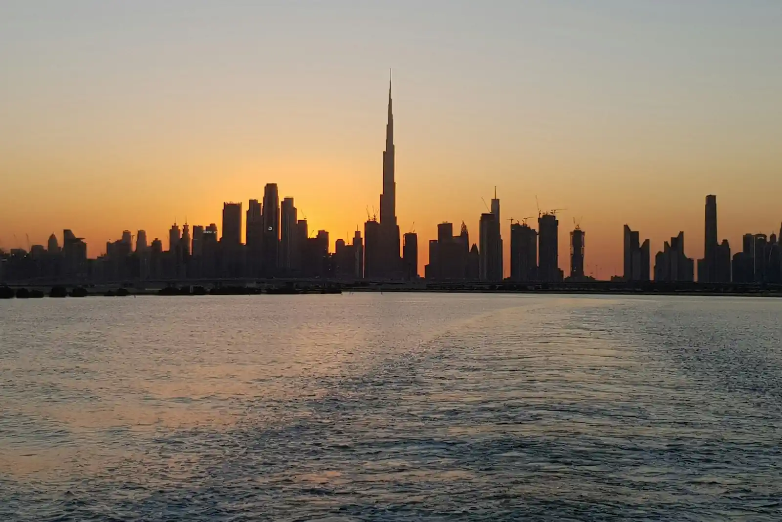 Dubai skyline with Burj Khalifa across the water at sunset