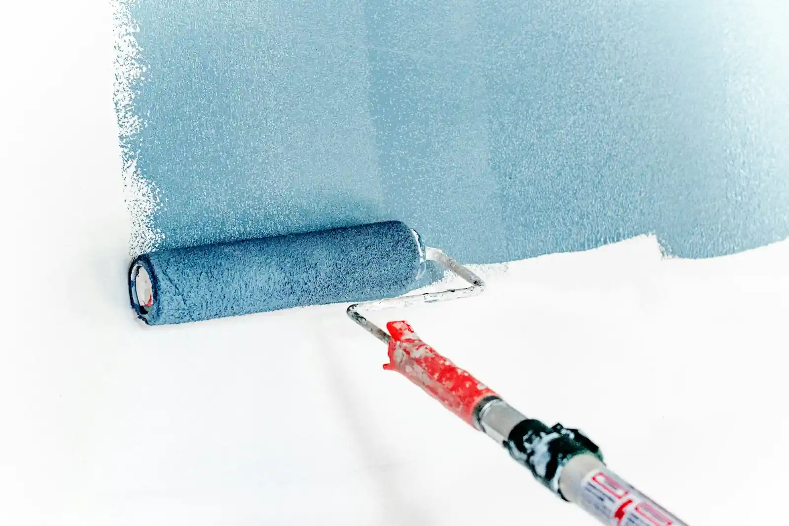 Paint roller applying paint to a white wall