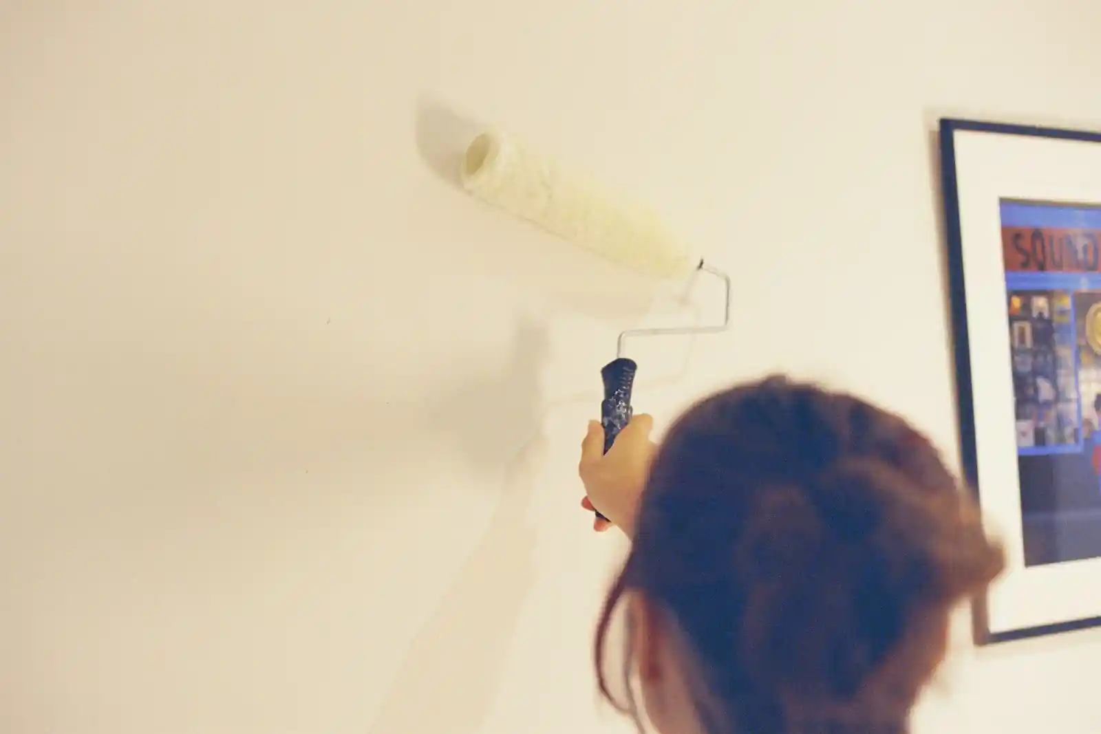 Person painting a pale wall with a roller