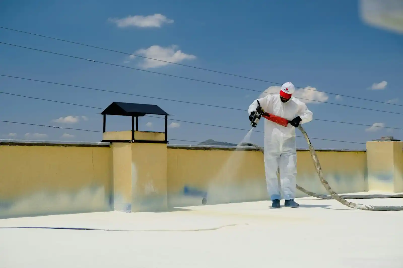 Worker in a protective coverall coating a flat roof